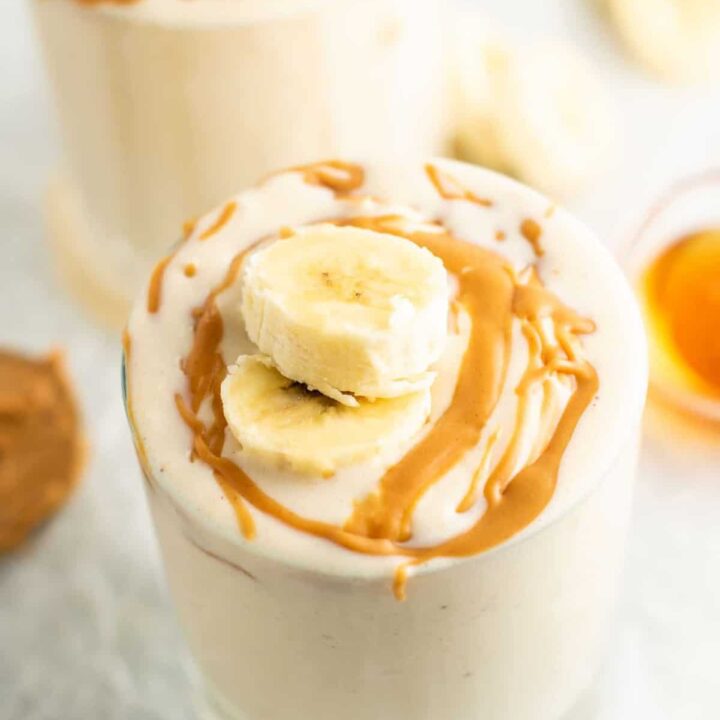 peanut butter and banana smoothie with sliced bananas and drizzled peanut butter on top