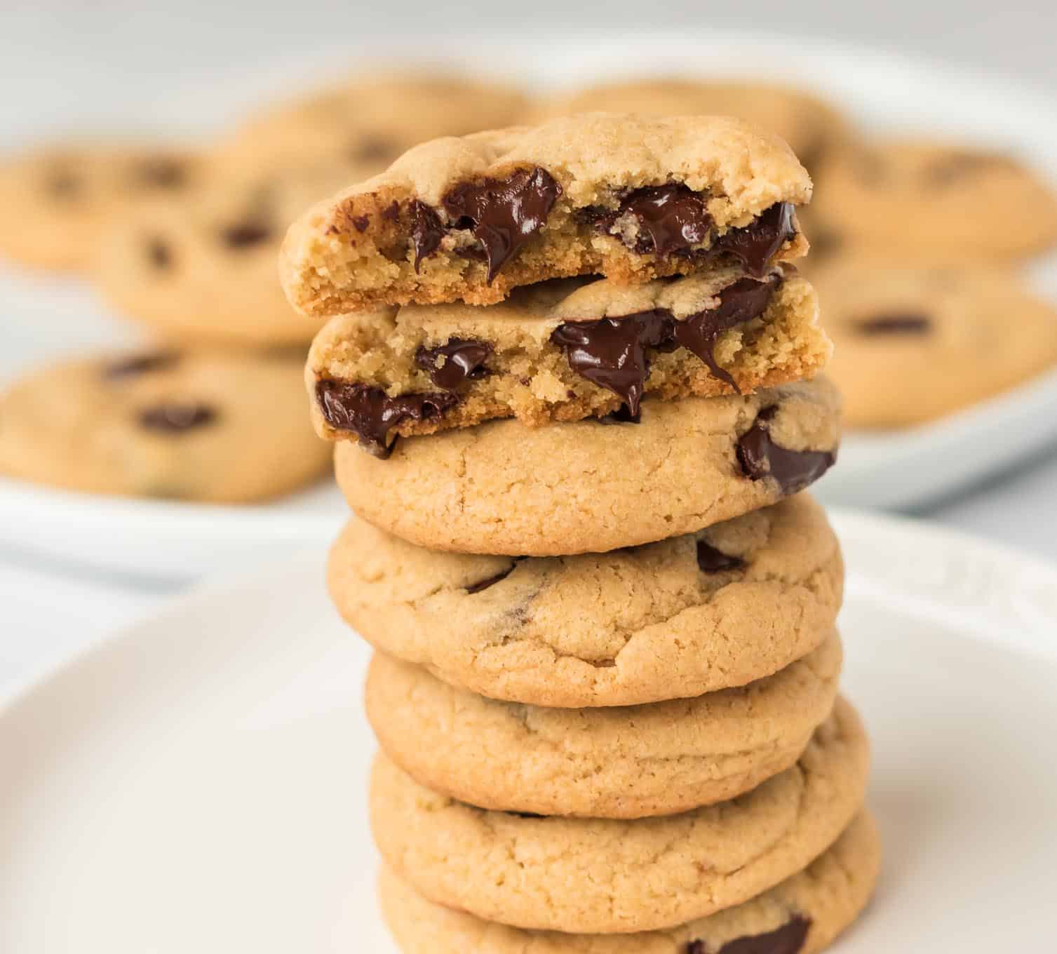 vegan chocolate chip cookies stacked with the top cookie split in half to show melted chocolate