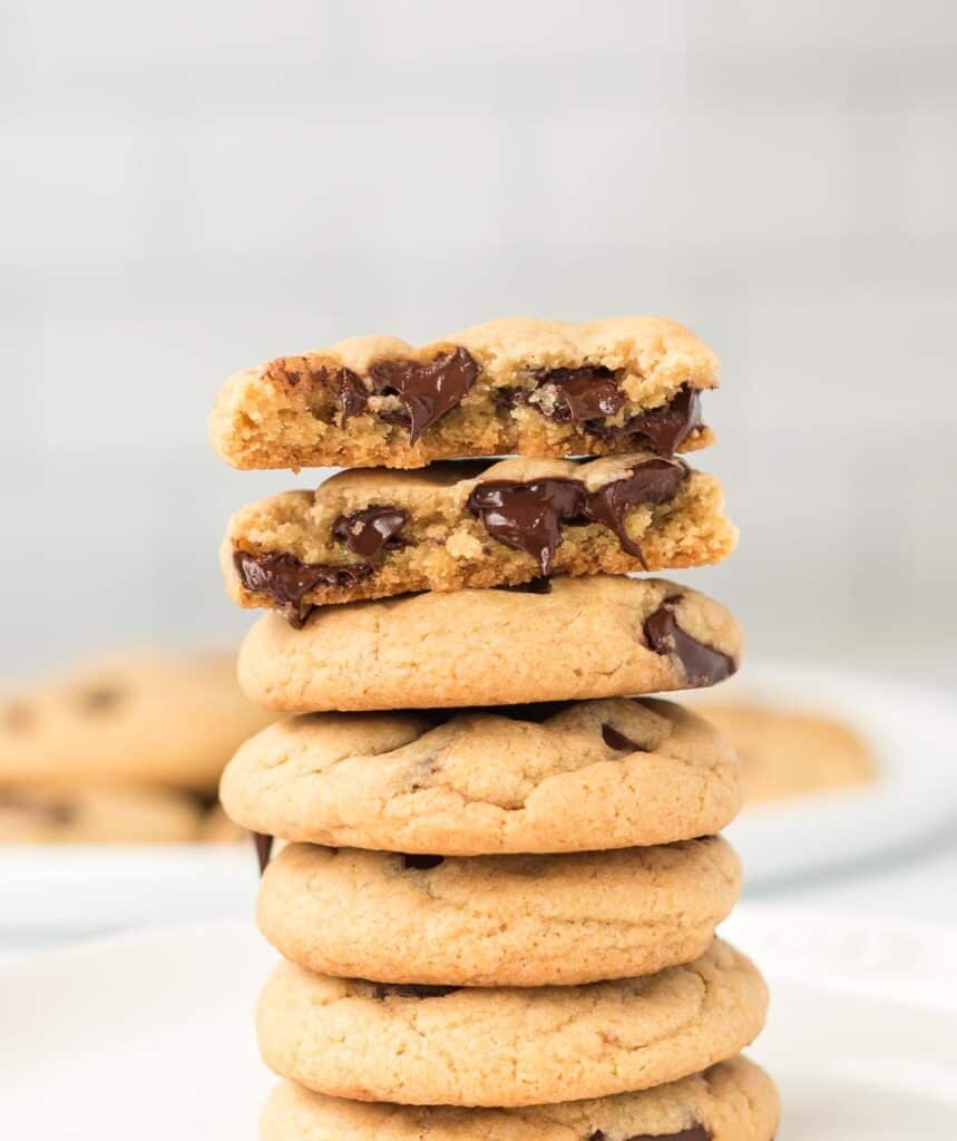 vegan chocolate chip cookies stacked with the top cookie split in half to show melted chocolate