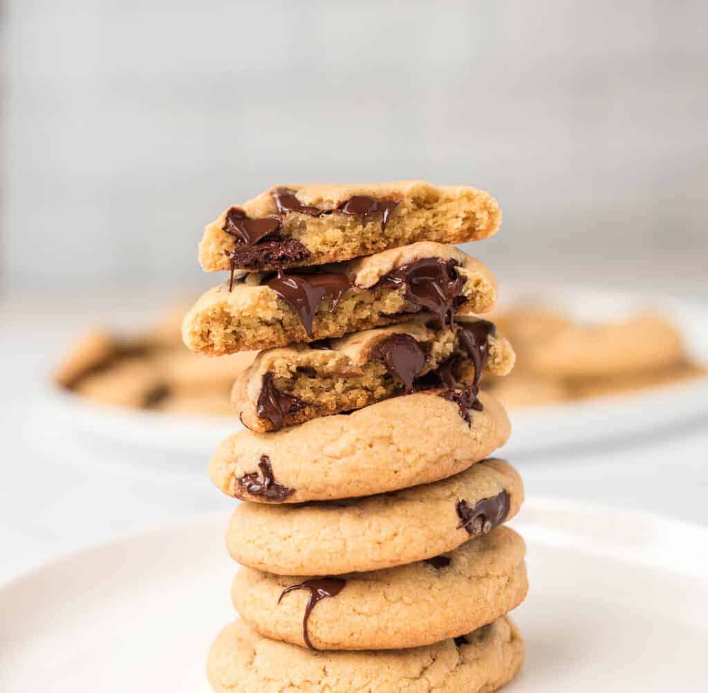 vegan chocolate chip cookies stacked with the top cookie split in half to show melted chocolate