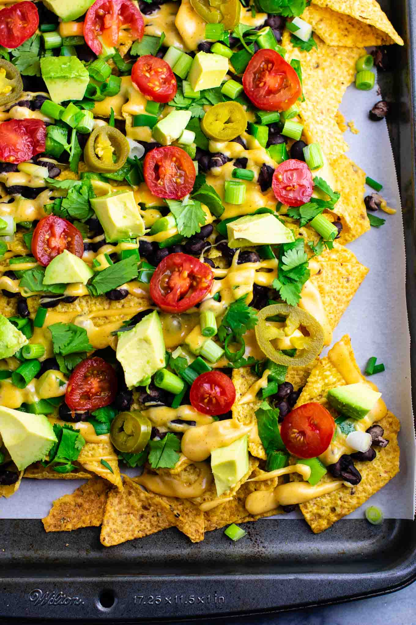 Loaded veggie nachos topped with homemade nacho cheese sauce. These are amazing! #veggienachos #vegetarian #nachocheese #nachocheesesauce