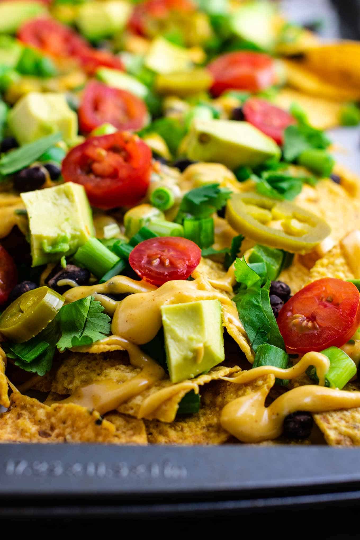 Loaded veggie nachos topped with homemade nacho cheese sauce. These are amazing! #veggienachos #vegetarian #nachocheese #nachocheesesauce