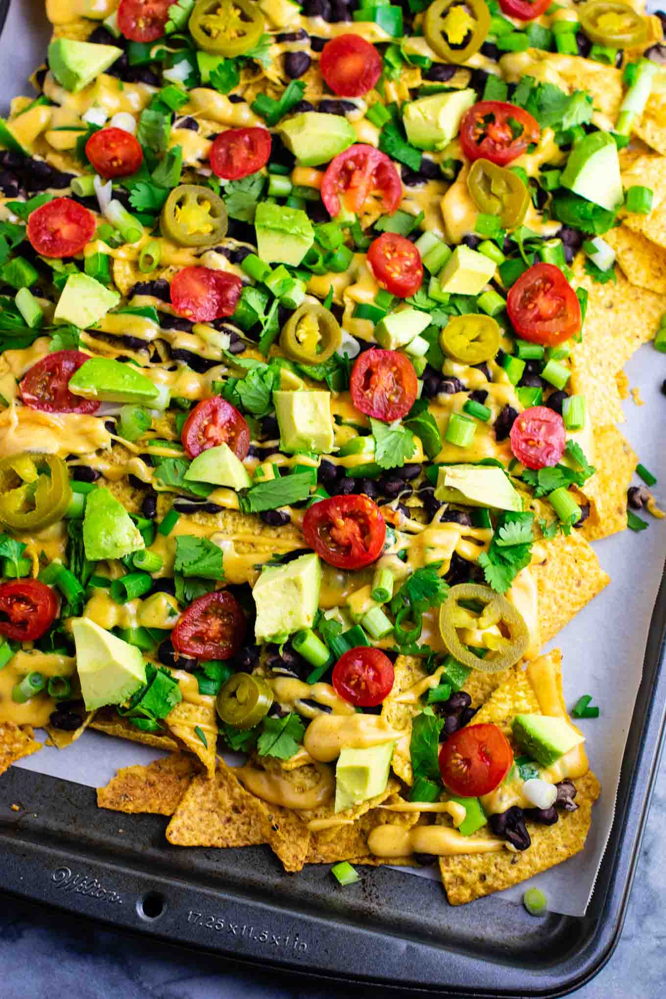 Loaded veggie nachos topped with homemade nacho cheese sauce. These are amazing! #veggienachos #vegetarian #nachocheese #nachocheesesauce