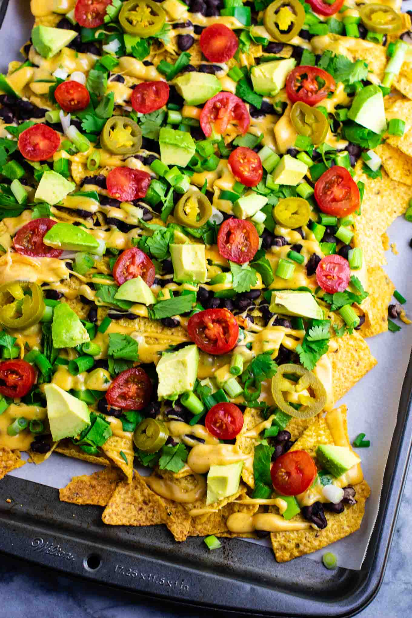 Loaded veggie nachos topped with homemade nacho cheese sauce. These are amazing! #veggienachos #vegetarian #nachocheese #nachocheesesauce