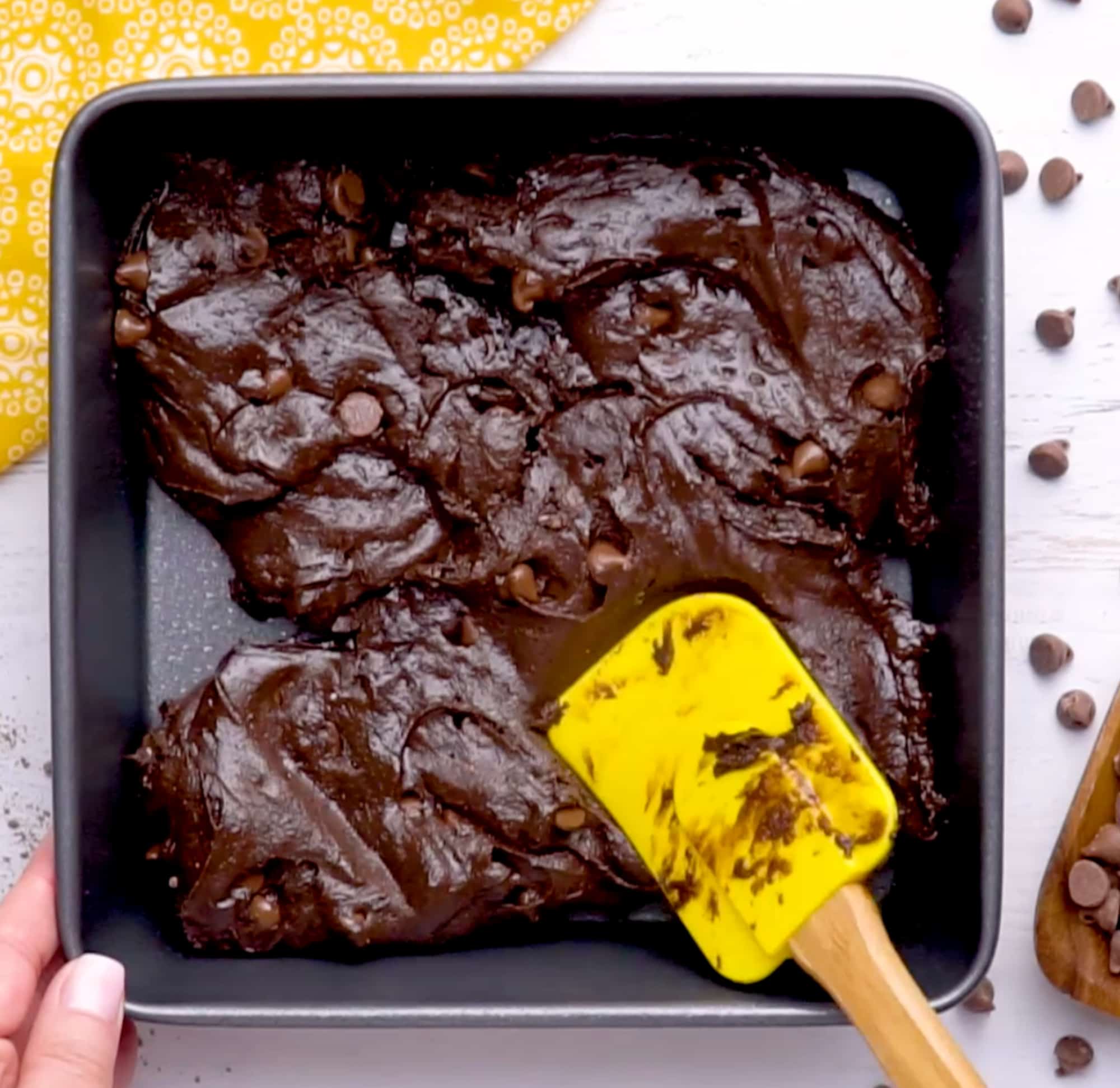spreading the brownie batter into a baking dish using a rubber spatula