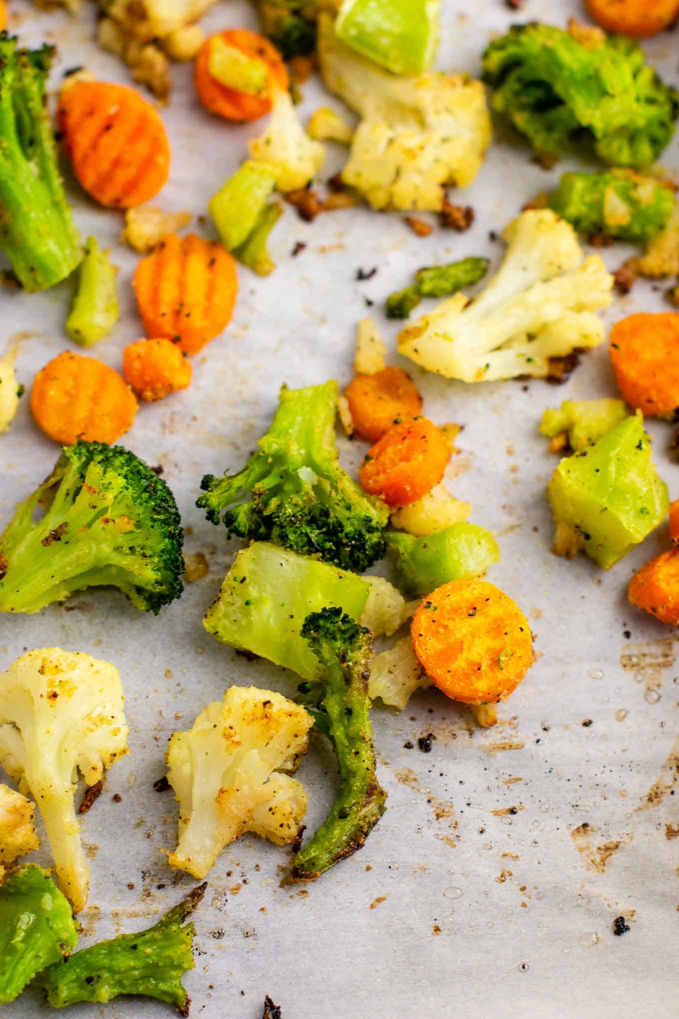 broccoli, cauliflower, and carrots roasted on a parchment paper lined baking sheet