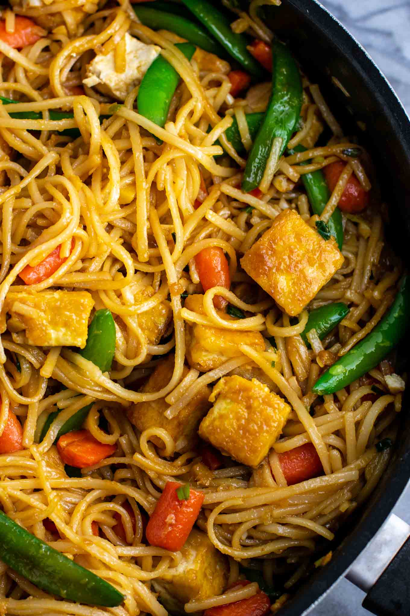 Tofu stir fry noodles with sugar snap peas and carrots. Homemade 3 ingredient stir fry sauce makes this taste amazing! #tofu #stirfrynoodles #stirfry #vegan #dinner #stirfryrecipe #vegetarian #tofustirfy