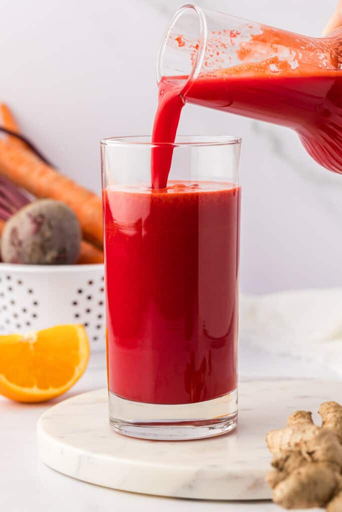 pouring beet and carrot juice into a glass