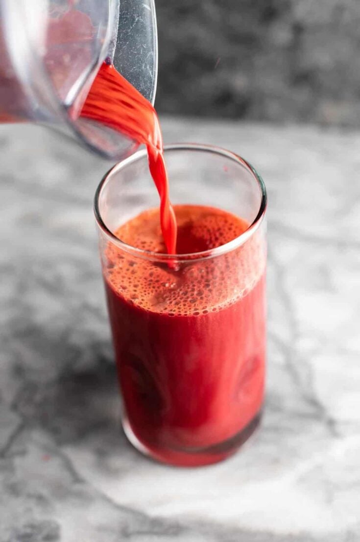 beet and carrot juice being poured into a glass