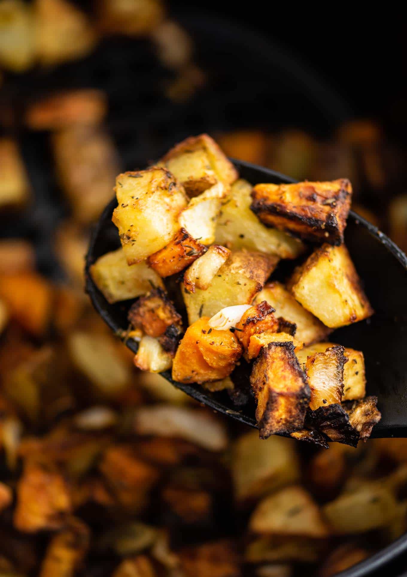 sweet potatoes, russet potatoes, and onions on a black spoon