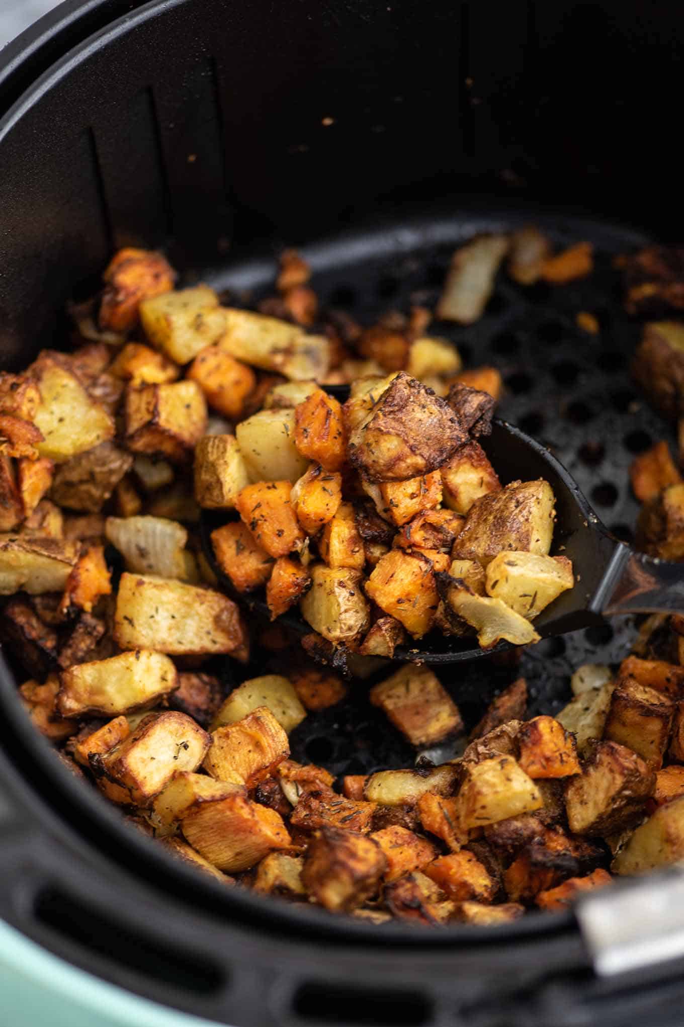 a spoon taking a scoop of the finished potato hash