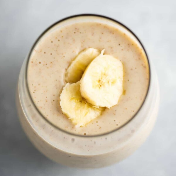 banana smoothie in a glass with sliced bananas on top