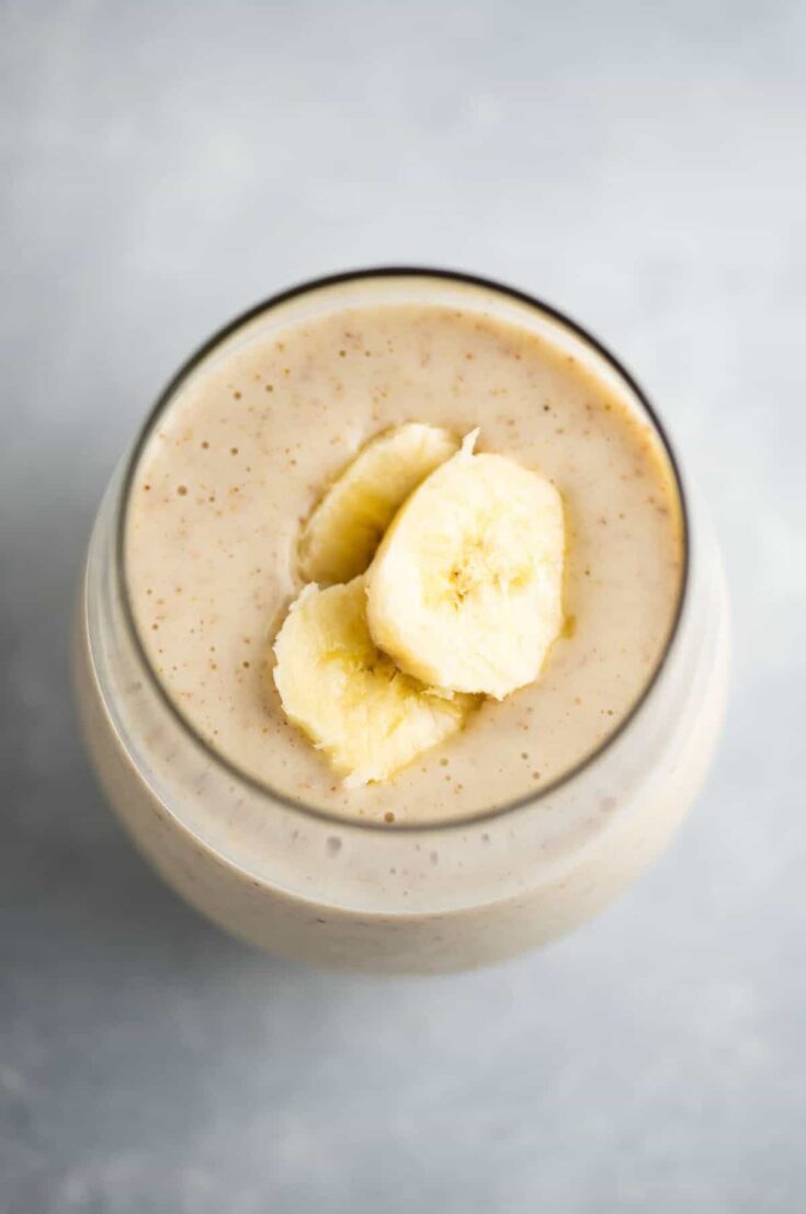 banana smoothie in a glass with sliced bananas on top