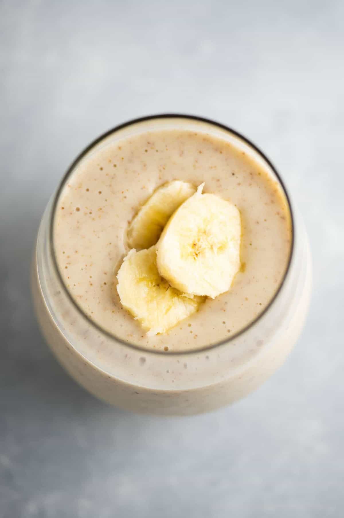 banana smoothie in a glass with sliced banana on top