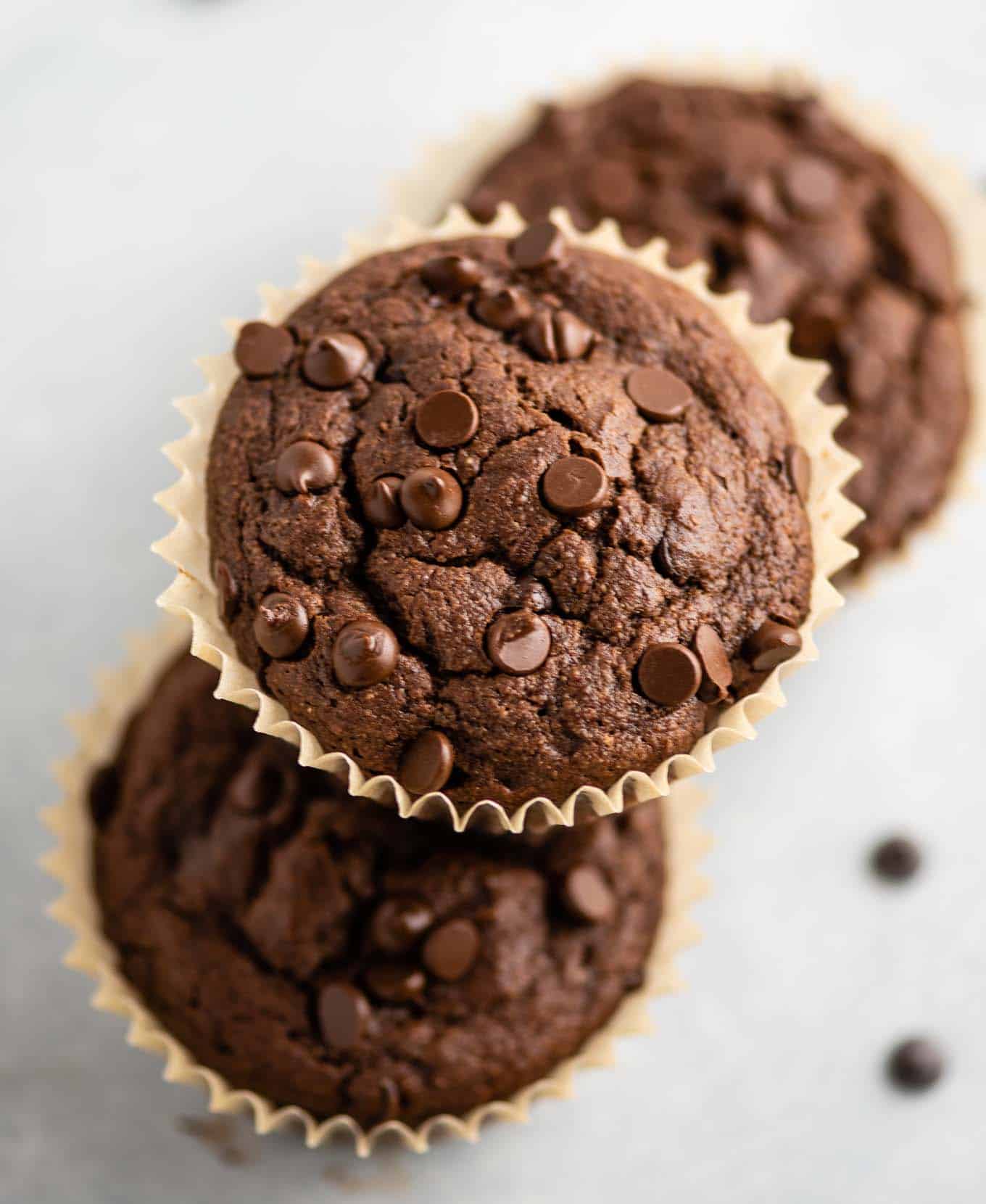 one chocolate muffin stacked on two other muffins