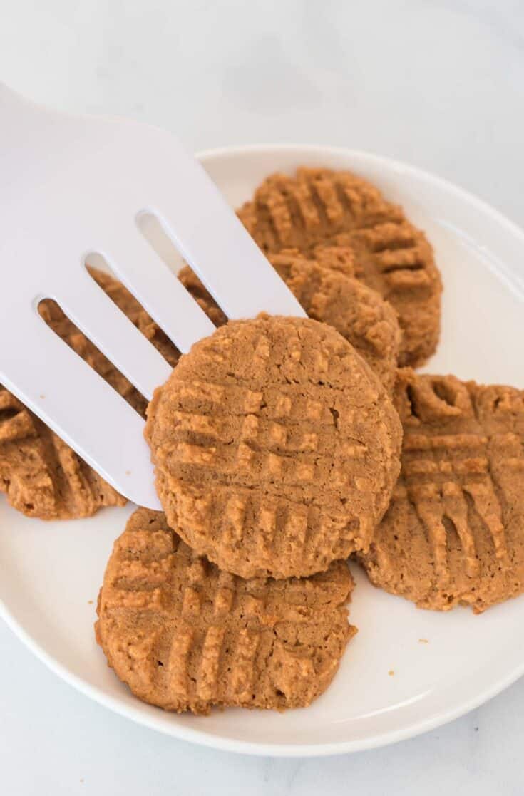 a spatula placing a peanut butter cookie onto a plate