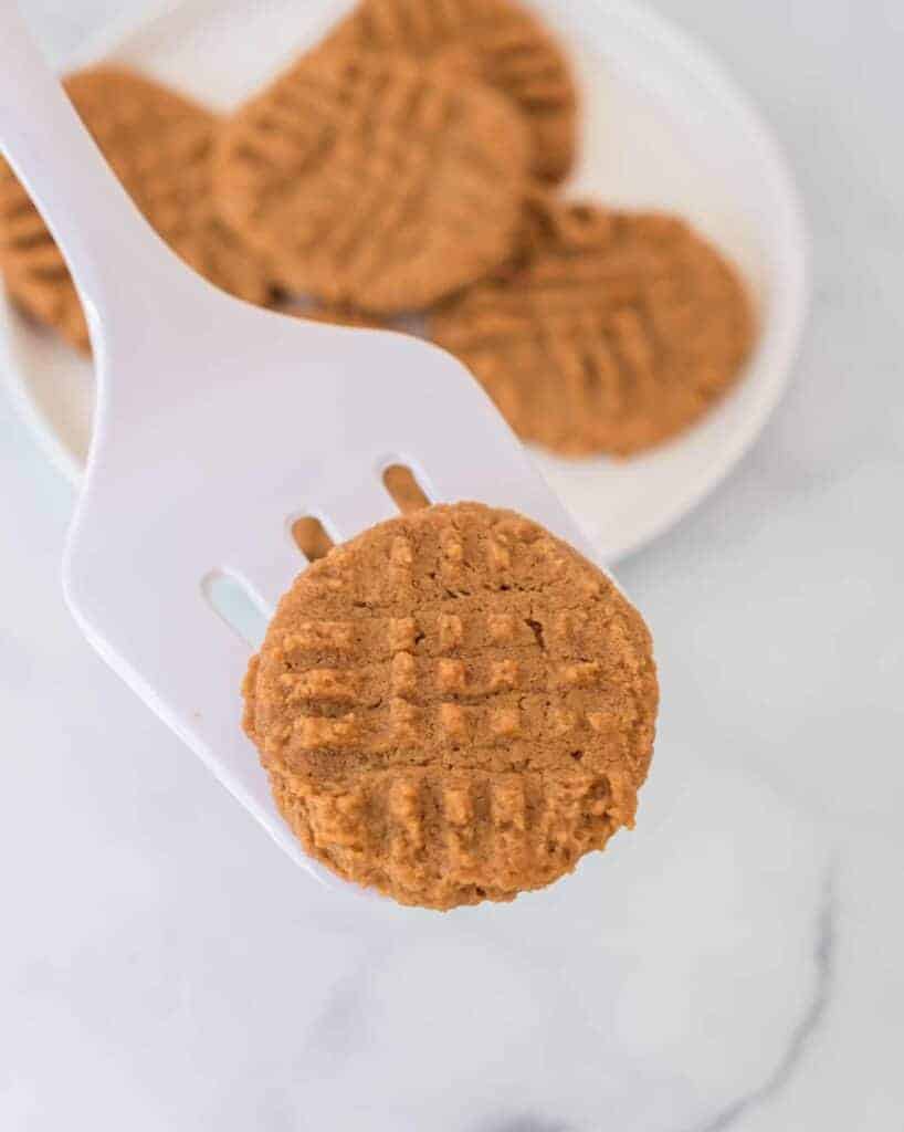 white spatula holding a flourless peanut butter cookie