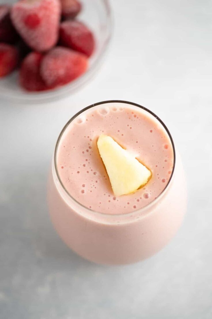 strawberry pineapple smoothie recipe with a piece of frozen pineapple on top