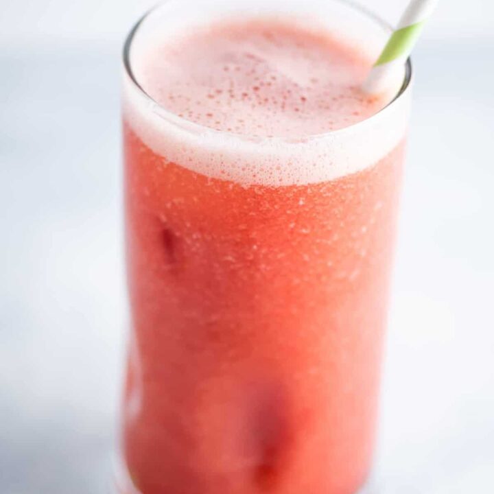 watermelon juice in a glass with a green and white straw