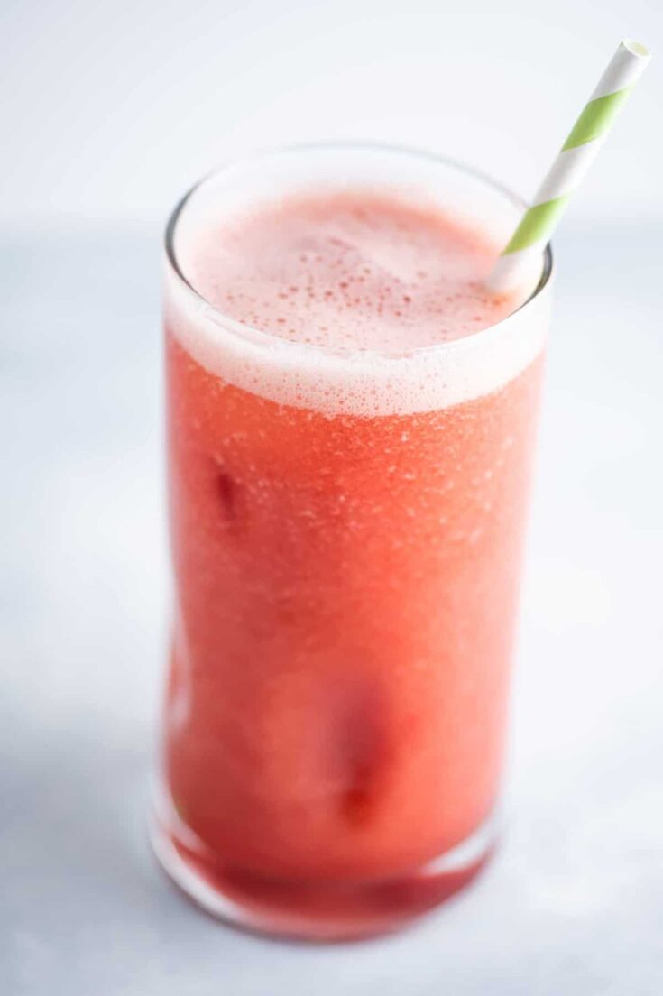 watermelon juice in a glass with a green and white straw