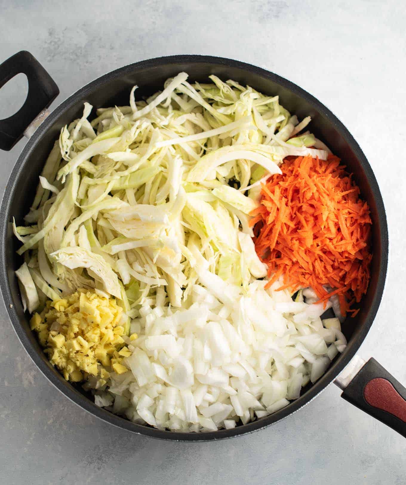 raw ginger, onion, cabbage, and carrots in a large skillet