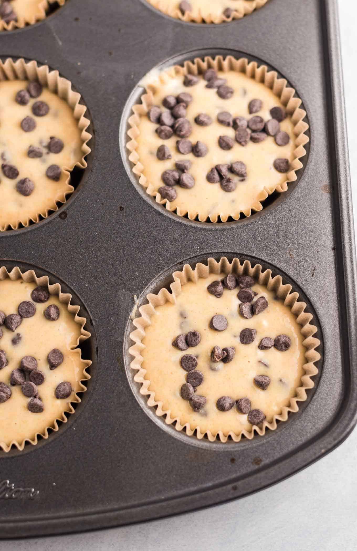 muffin batter in the muffin tins topped with extra mini chocolate chips