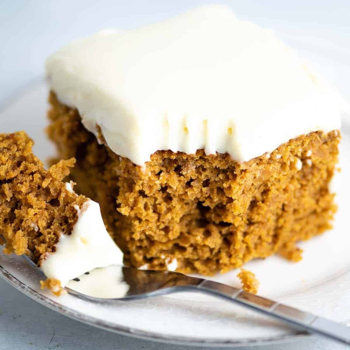 pumpkin cake recipe with cream cheese frosting slice on a plate with a bite taken out