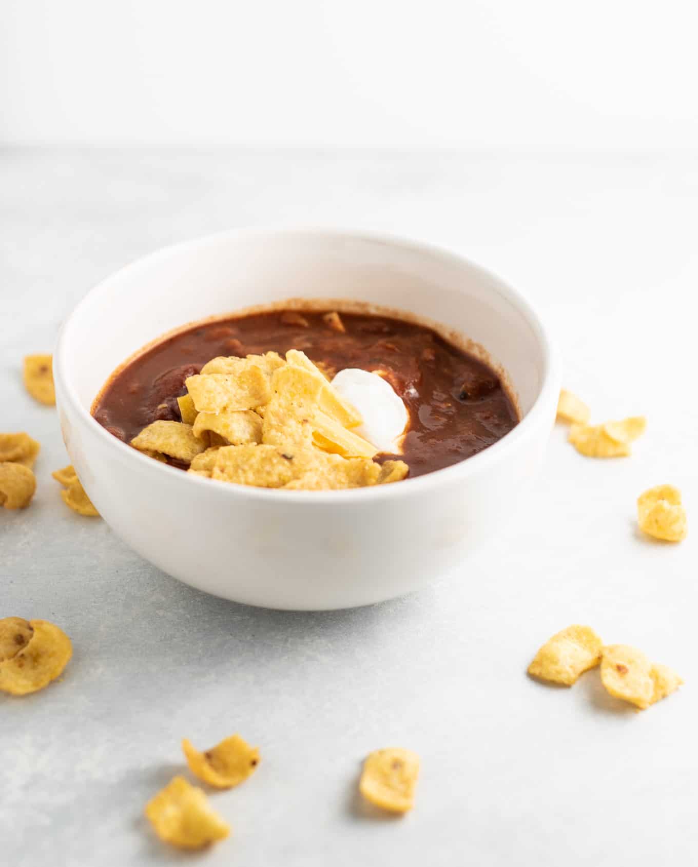 chili in a bowl with fritos, sour cream, and cheese