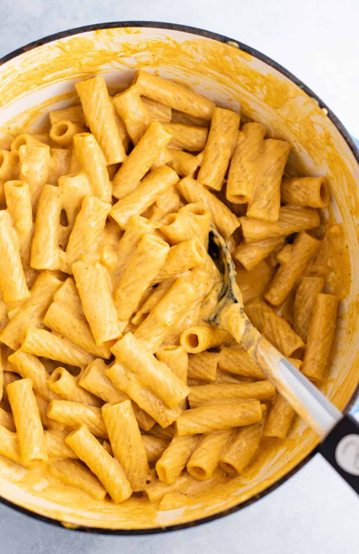 rigatoni mixed with pumpkin pasta sauce with a spoon in the dish