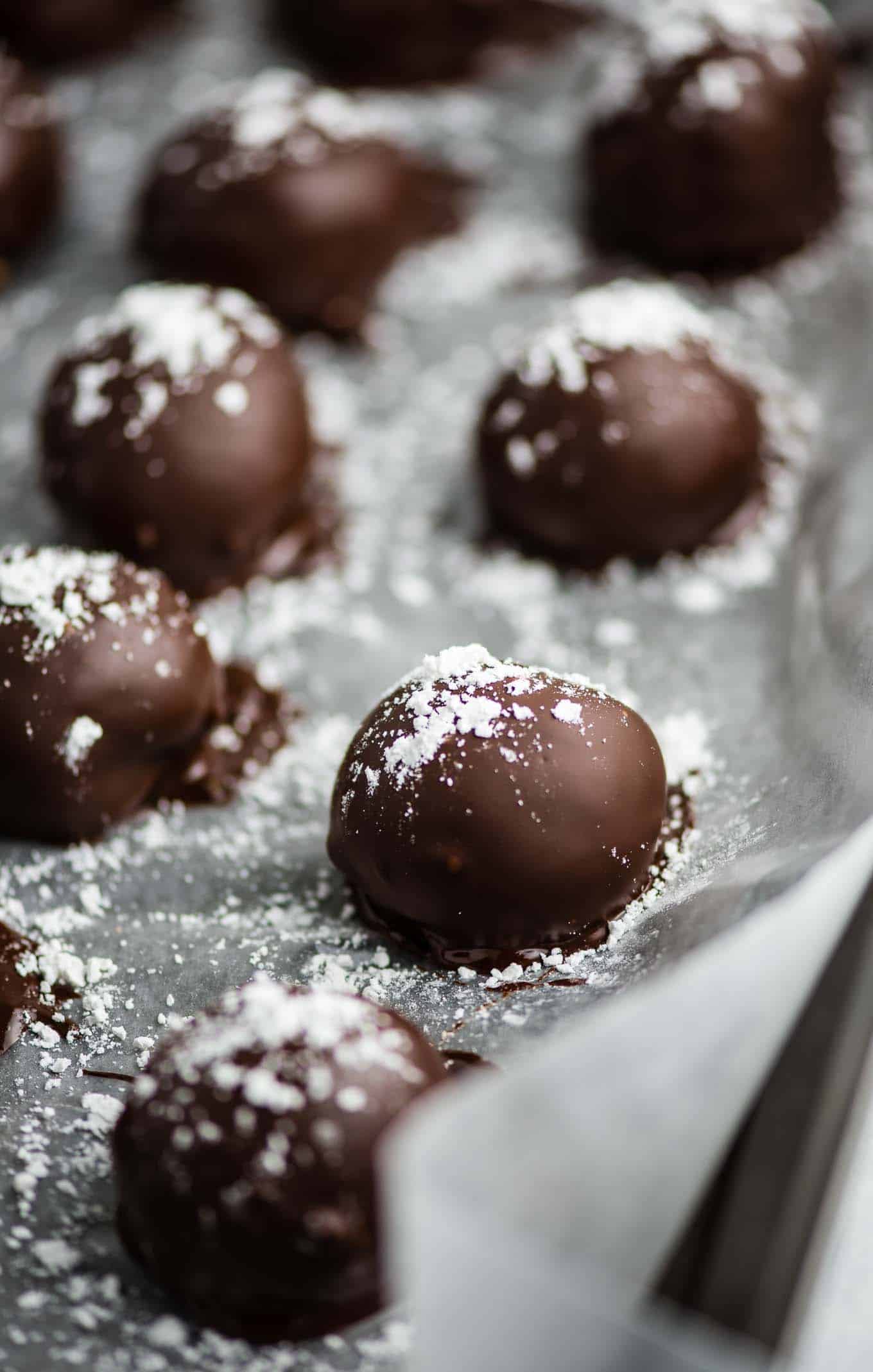 truffles lined up on the baking sheet sprinkled with powdered sugar