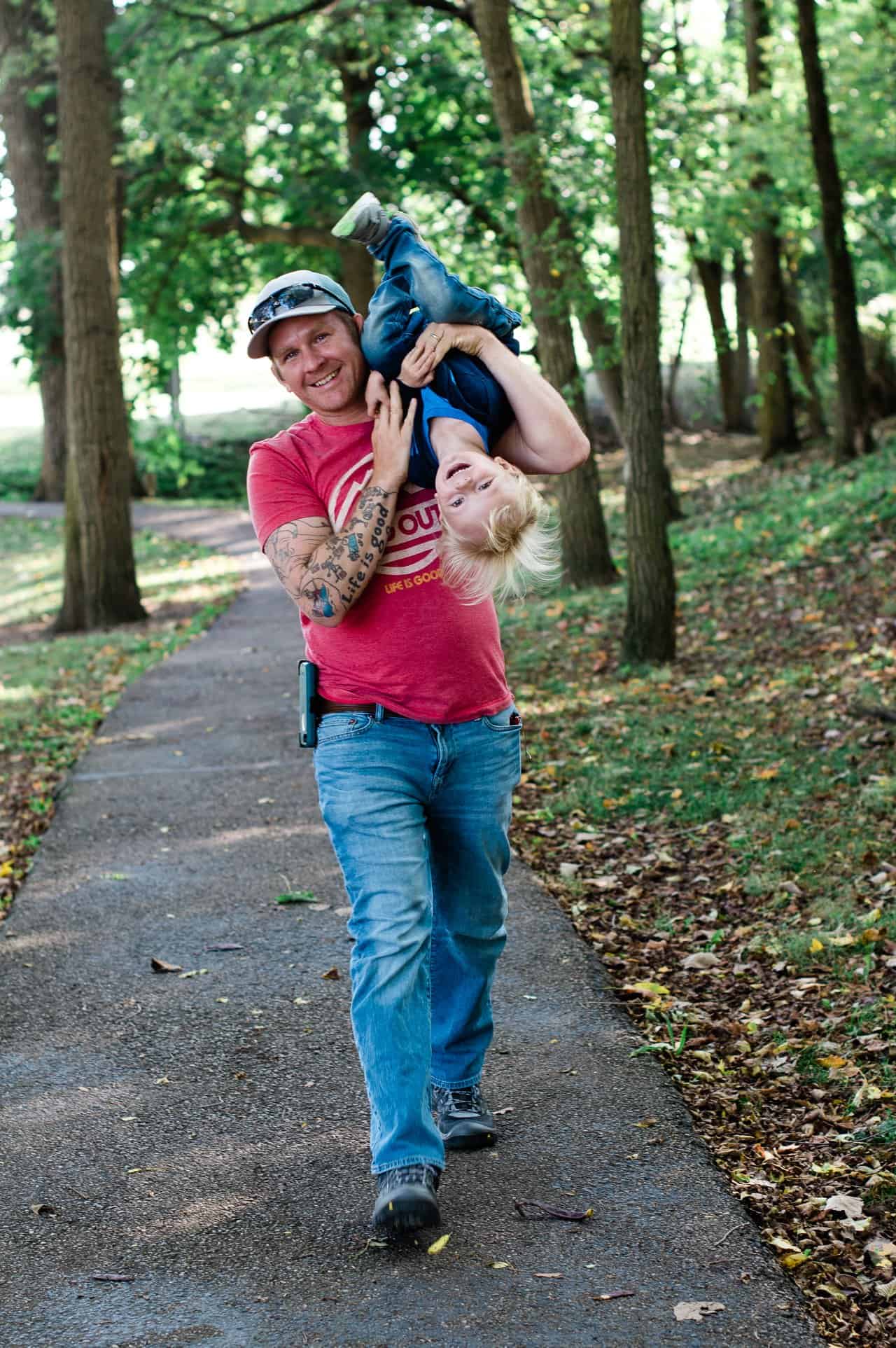 a dad holding his toddler upside down while walking