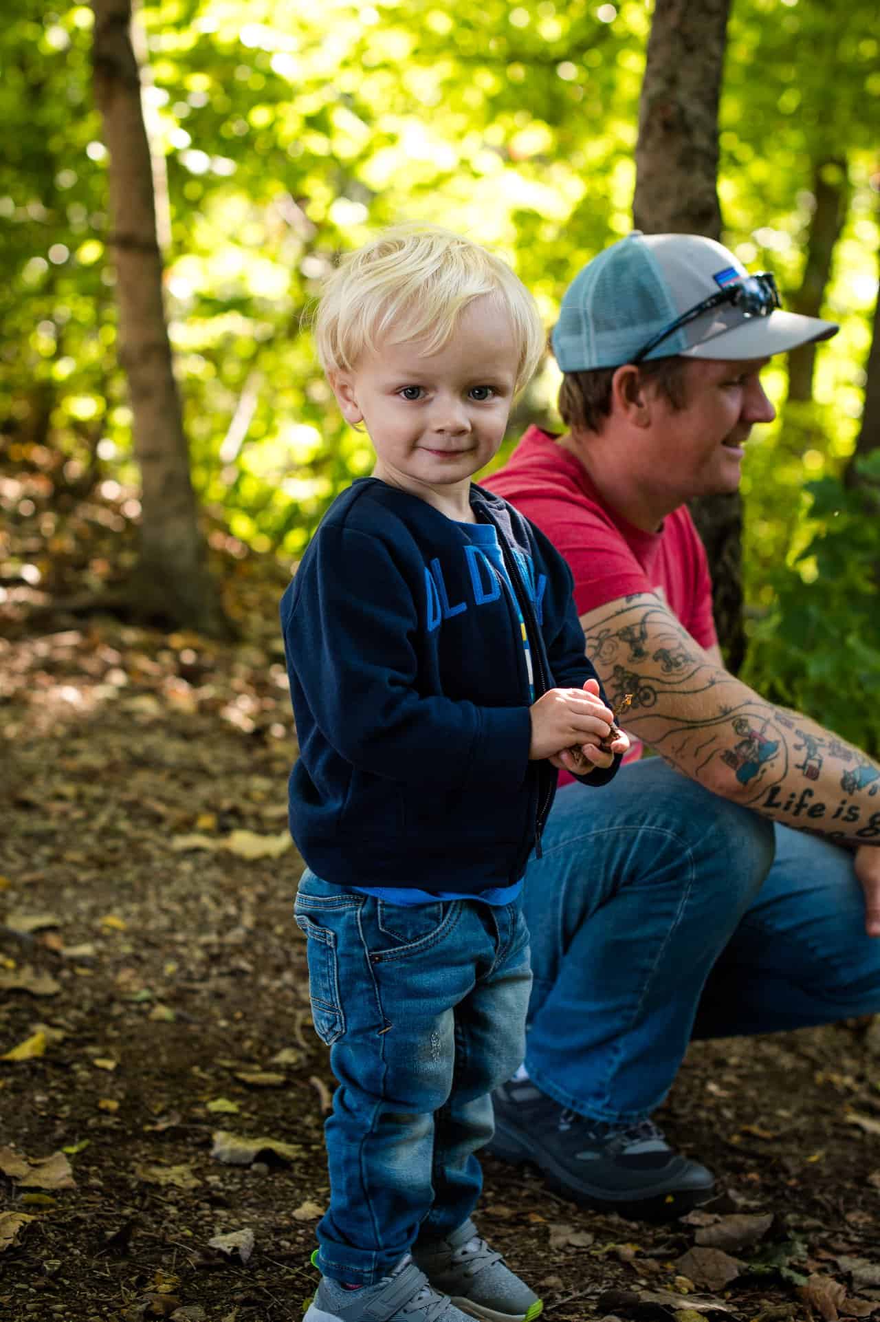 toddler boy smiling with dad in the background