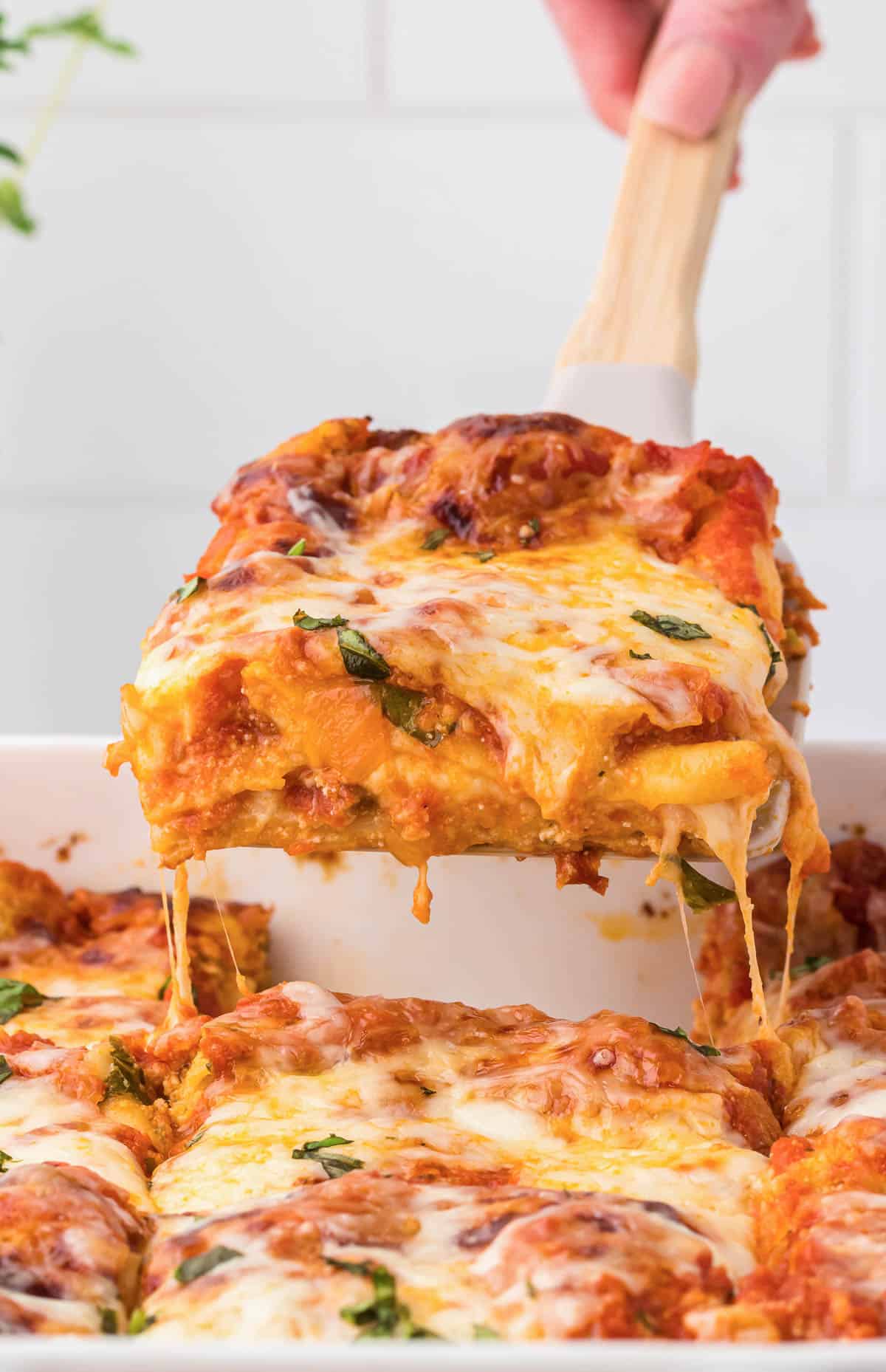 taking a piece of cheese lasagna from the pan