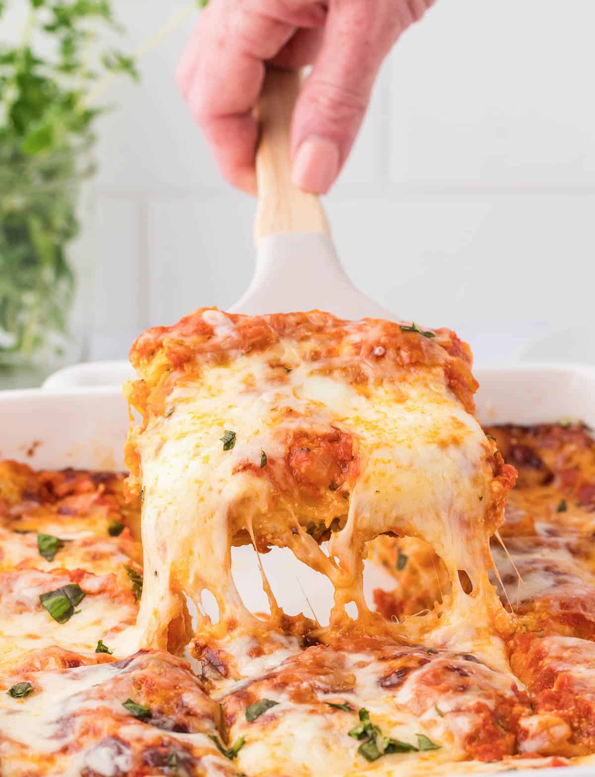 taking a piece of cheese lasagna from the pan