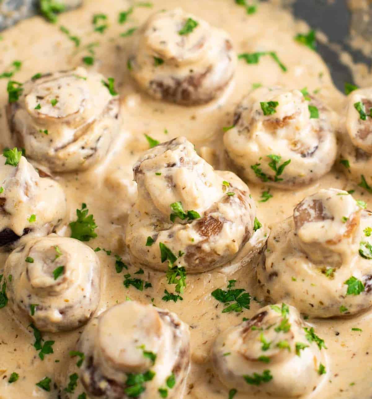 portobello mushrooms in cream sauce on a skillet sprinkled with fresh parsley