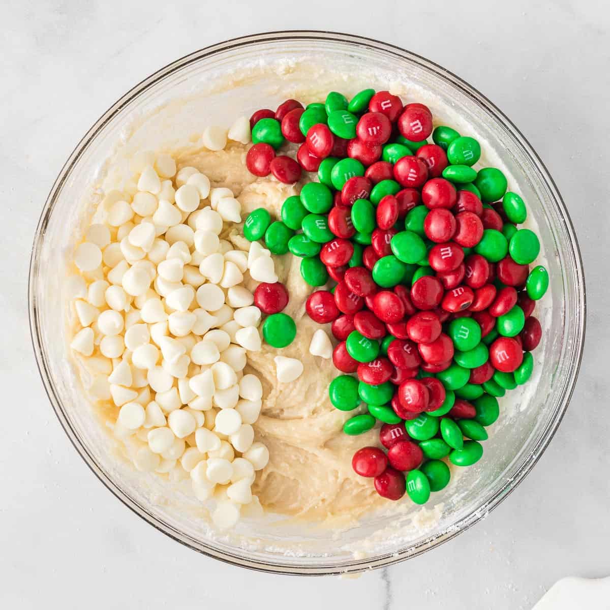 adding Christmas M&M's and white chocolate chips to the cake mix batter