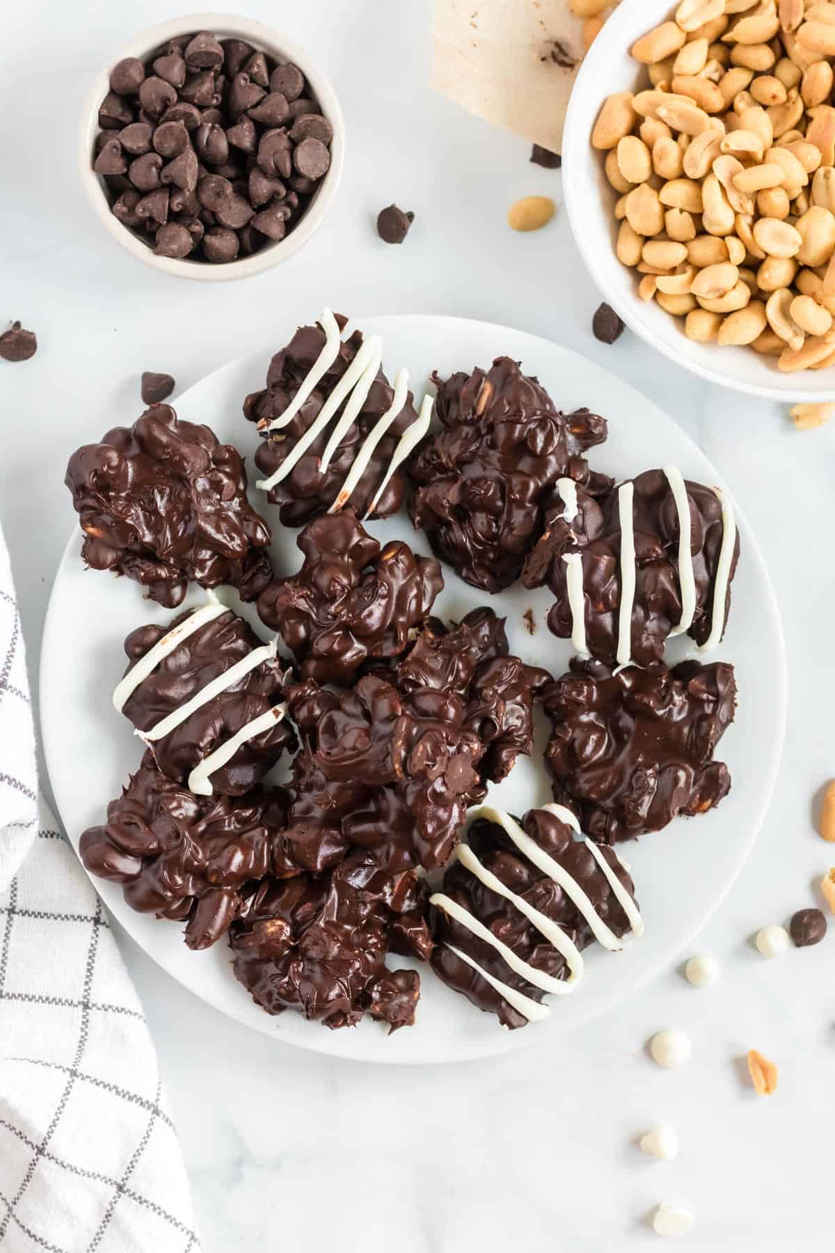 peanut clusters on a white plate, some plain and some drizzled with white chocolate