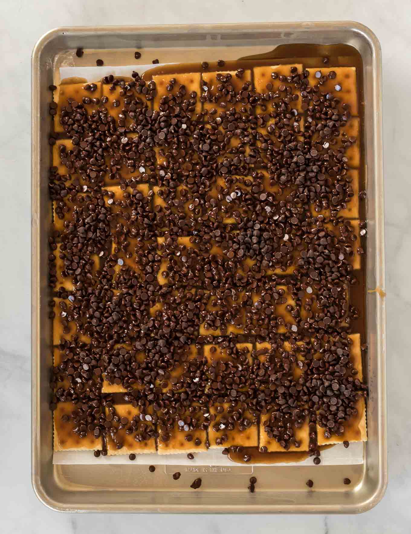 saltines on a baking sheet covered with toffee and chocolate chips