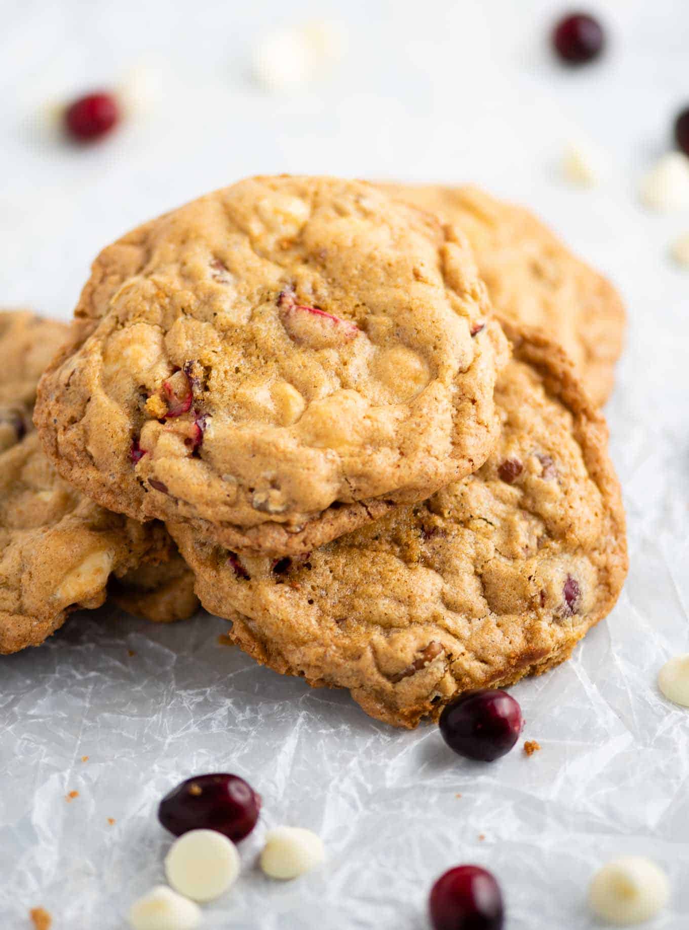 cookies on crumbled wax paper with cranberries and white chocolate chips in the background