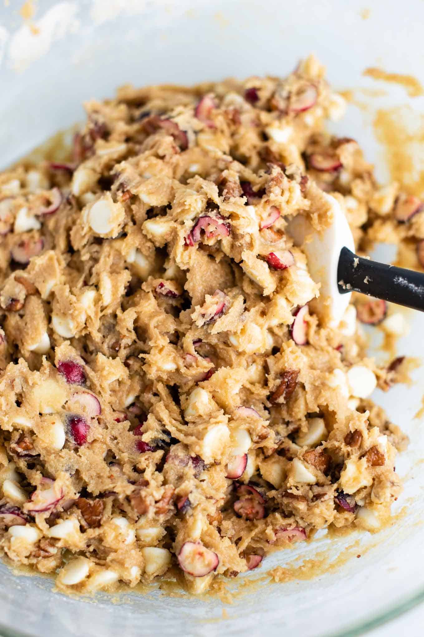 cranberry pecan cookie batter mixed together in a bowl with a rubber spatula