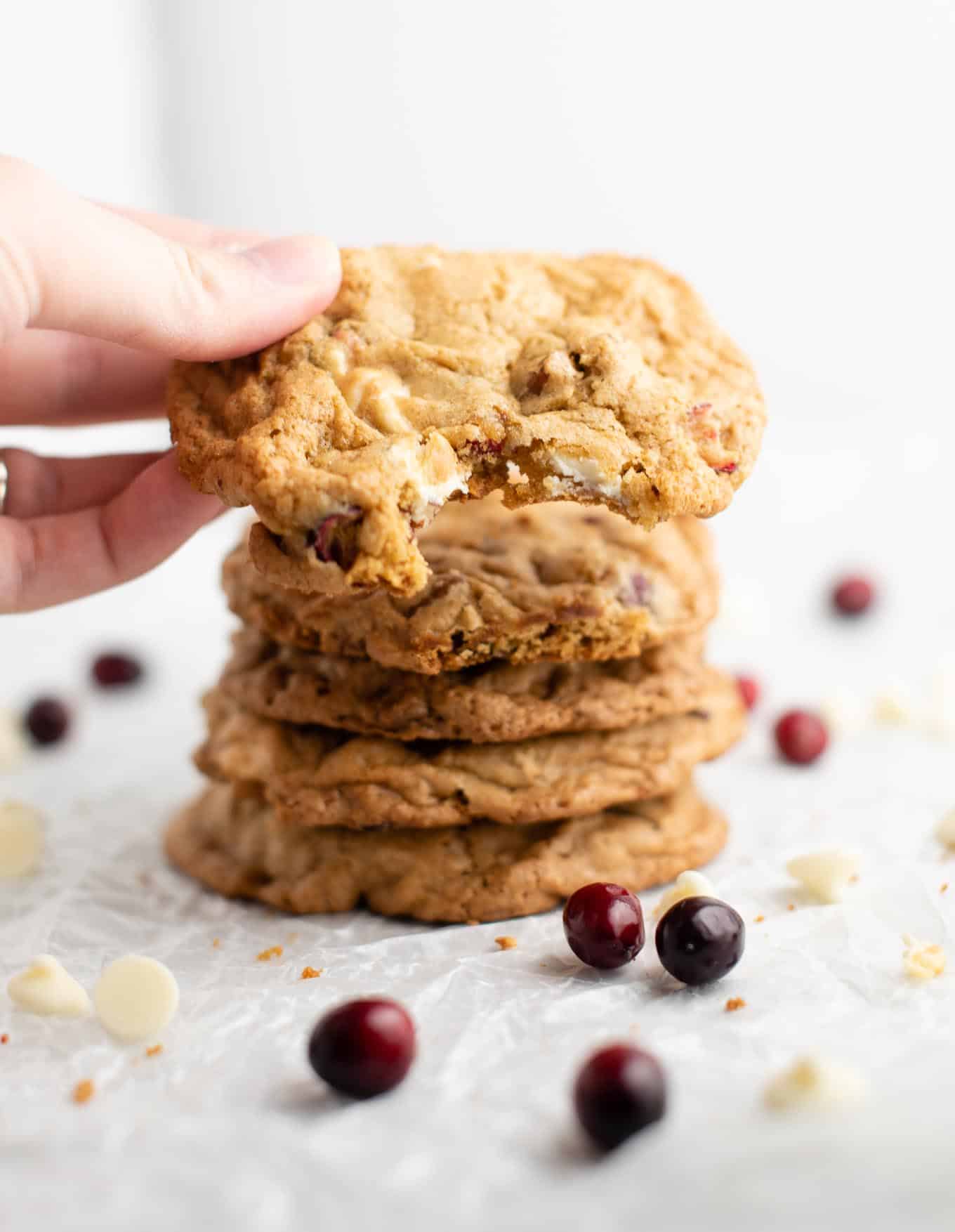 hand holding a cookie with a bite taken out in front of the camera