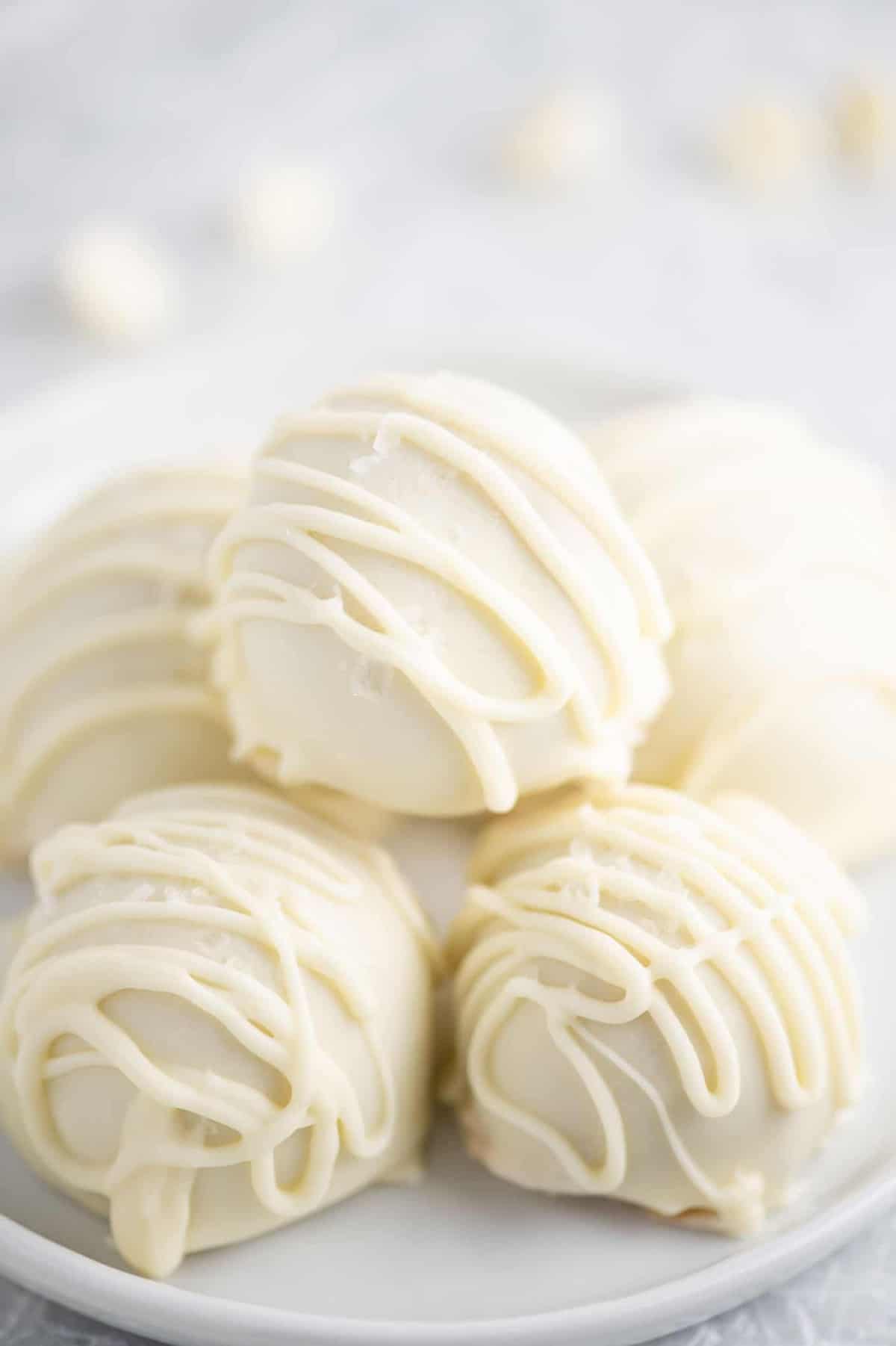 white chocolate peanut butter balls with drizzle stacked on a white plate