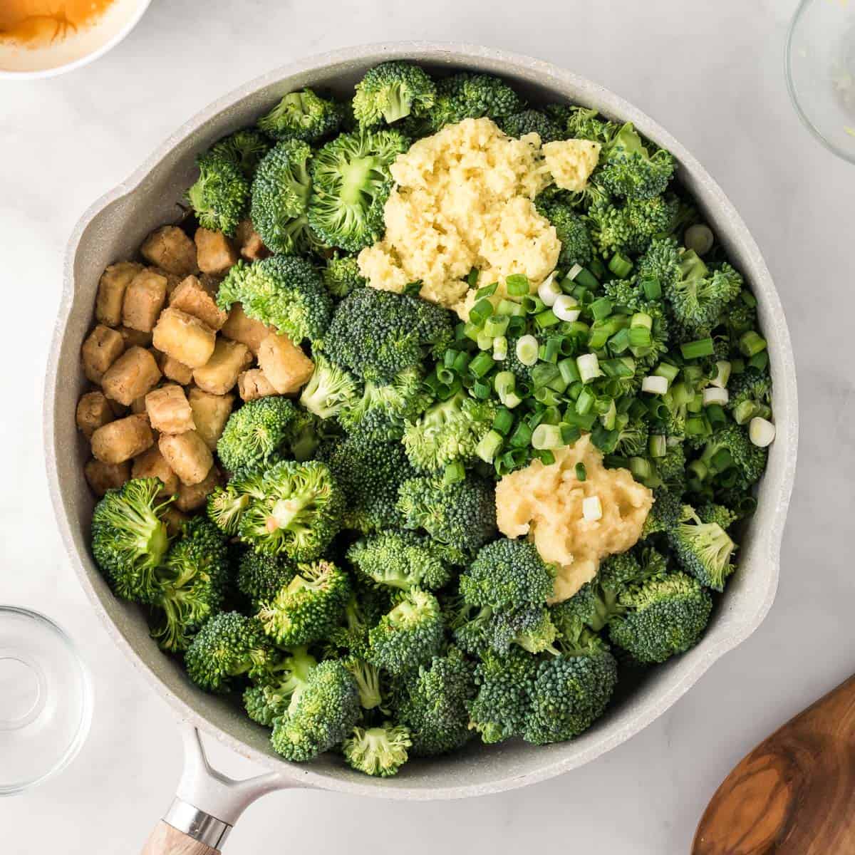 adding the broccoli, garlic, ginger, green onions, and stir fry sauce to the tofu