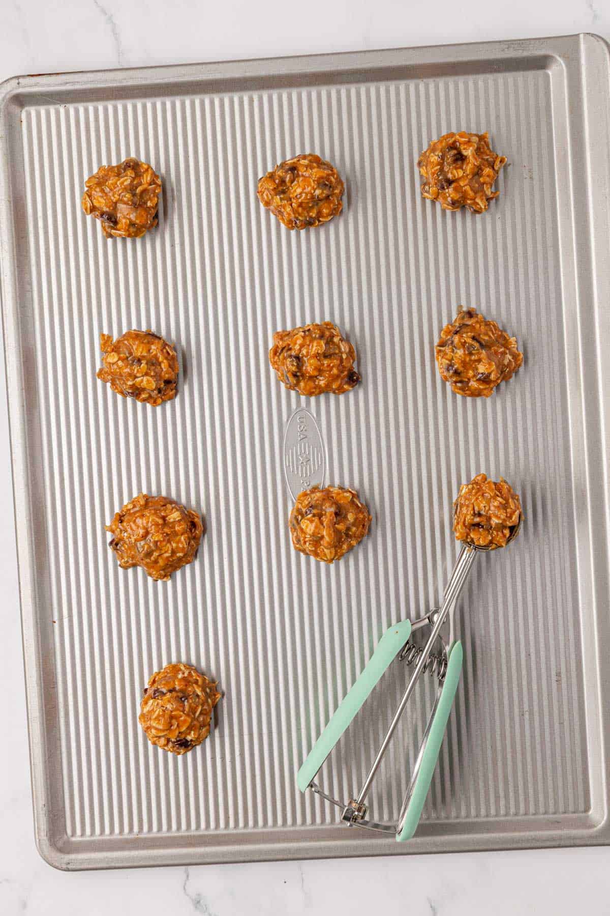 mini cookie scoop filled with batter on a baking sheet