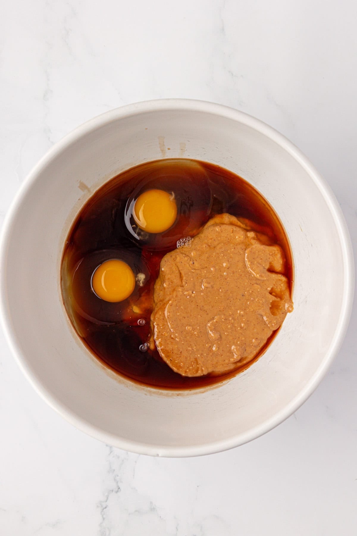 peanut butter, eggs, and maple syrup in a mixing bowl