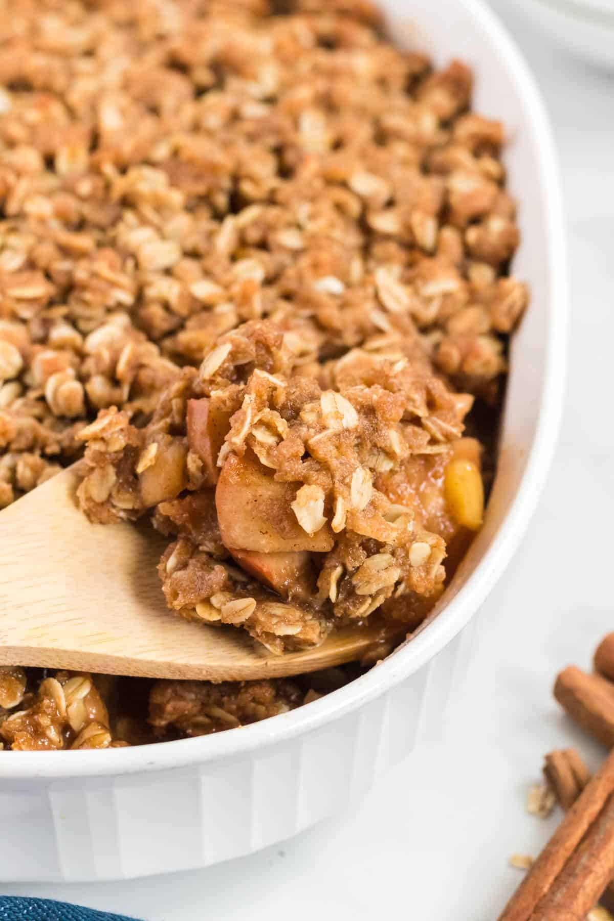 a wooden spoon scooping apple crisp from the pan