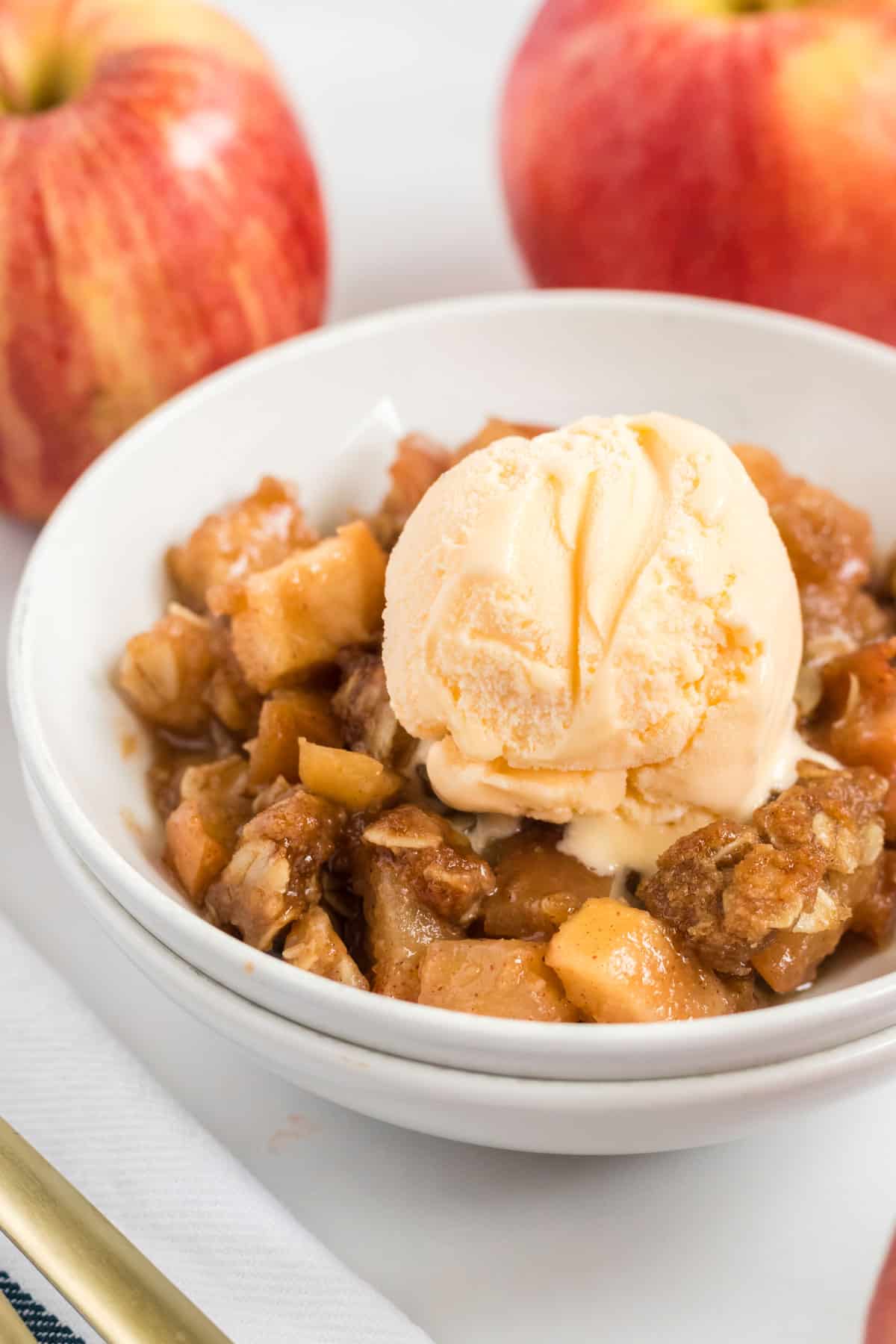 vegan apple crisp in a bowl topped with a scoop of ice cream