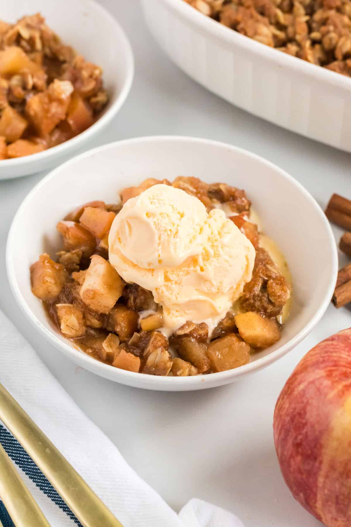 vegan apple crisp in a bowl topped with a scoop of ice cream