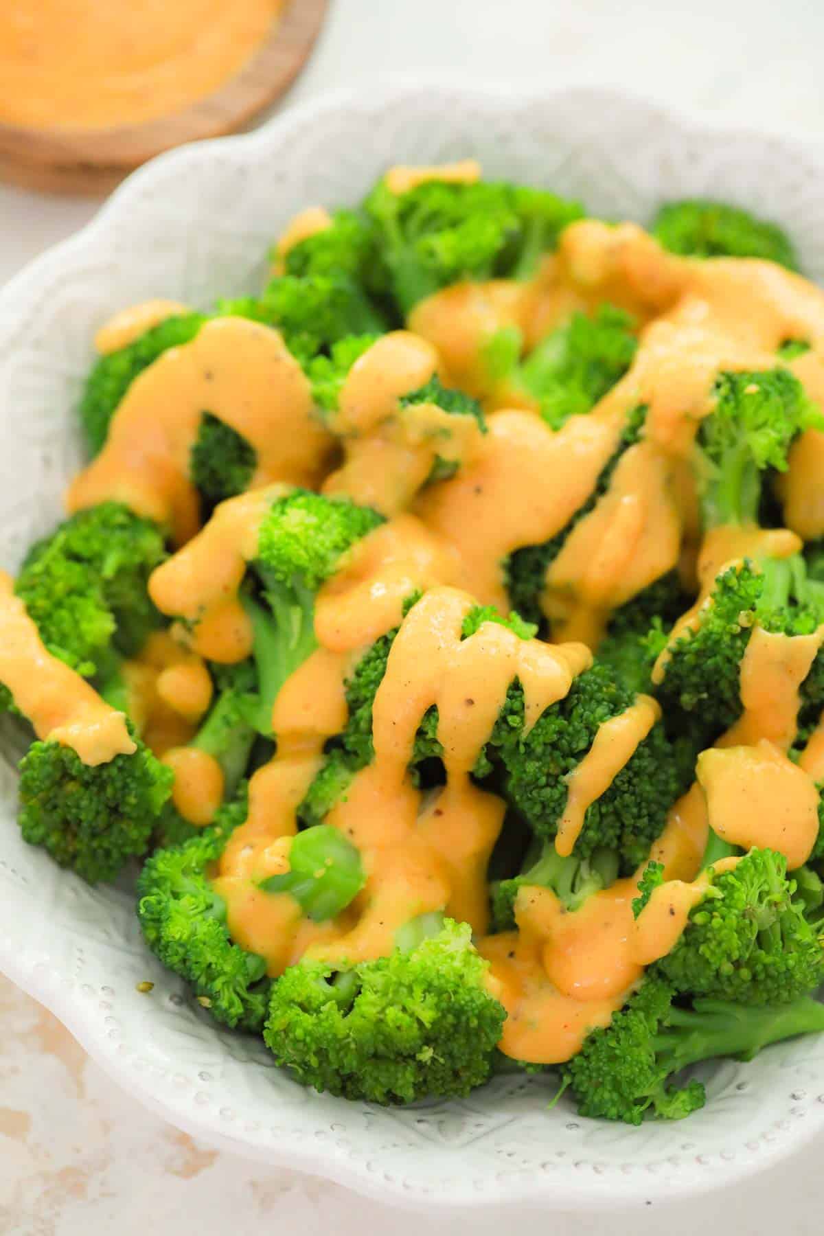 cheese sauce drizzled over broccoli on a plate