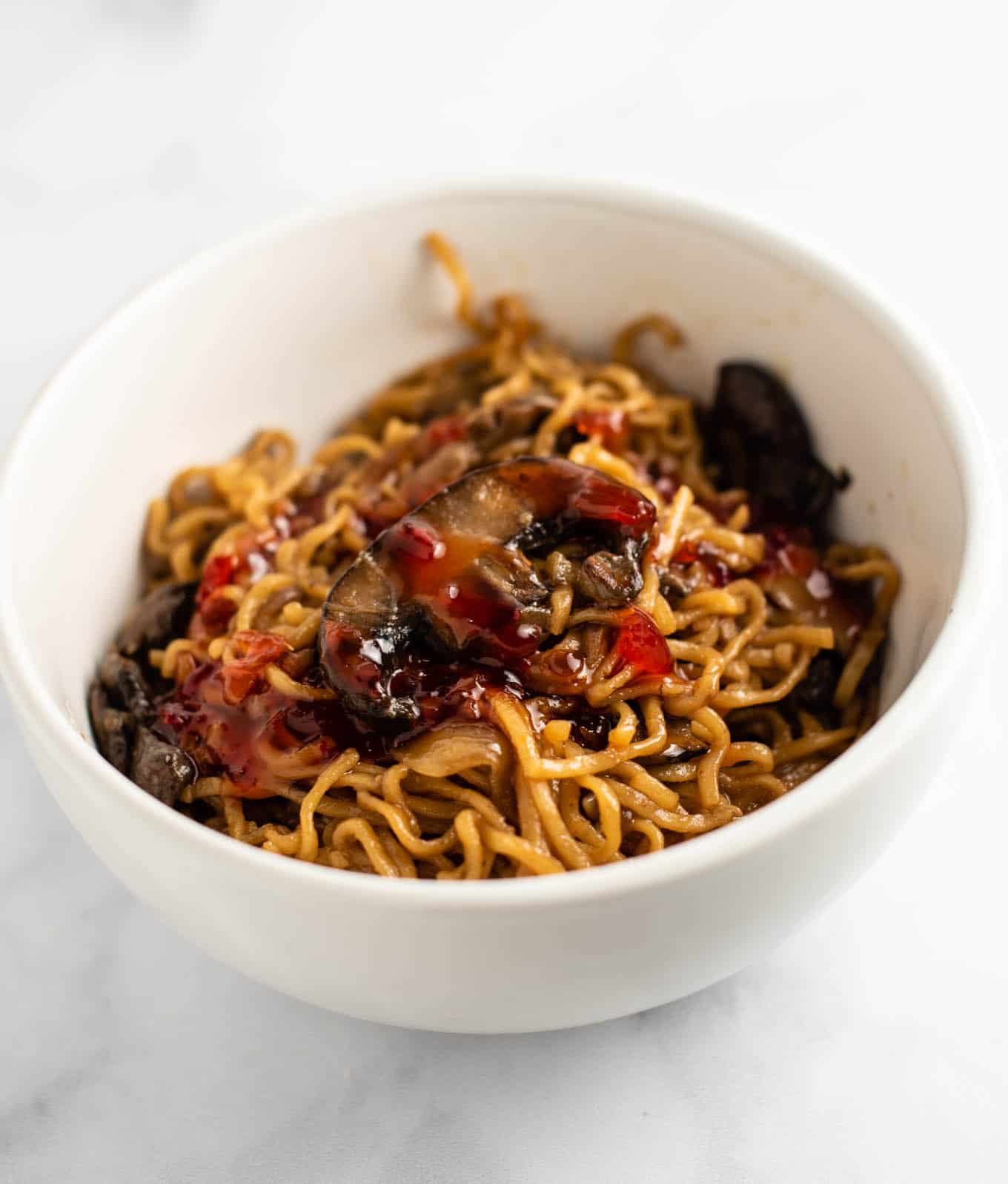 mushroom noodles with sweet chili sauce on top in a white bowl